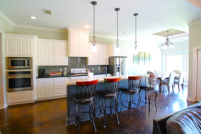 kitchen with stainless steel appliances, hanging light fixtures, and white cabinetry