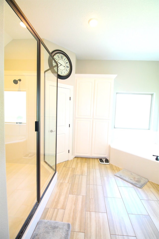 bathroom featuring independent shower and bath and lofted ceiling