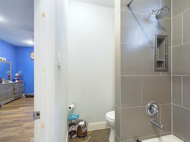 bathroom featuring toilet, hardwood / wood-style floors, and tiled shower