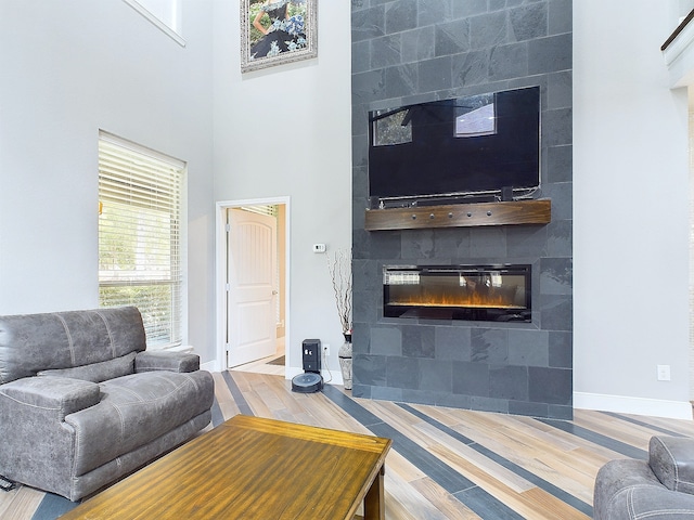 living room with hardwood / wood-style flooring, a tiled fireplace, and a high ceiling