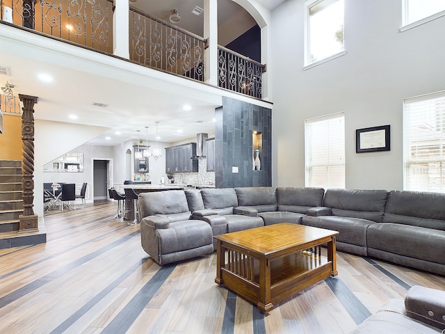 living room featuring light wood-type flooring, plenty of natural light, and a high ceiling