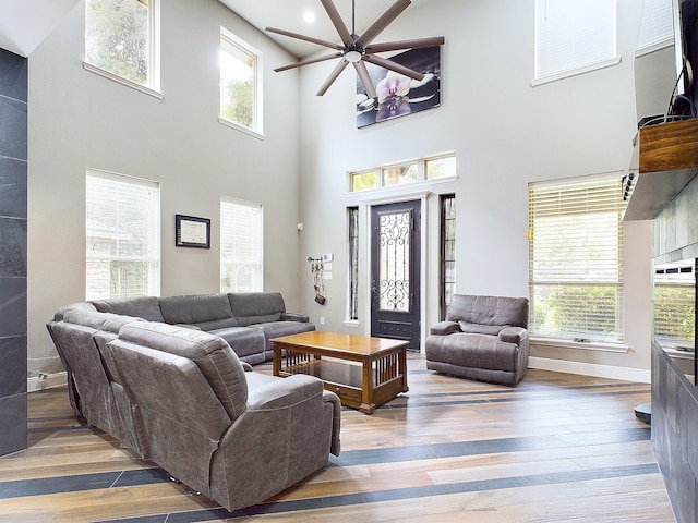 living room with wood-type flooring, a towering ceiling, and ceiling fan