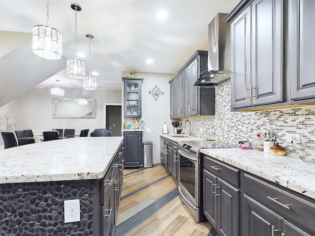 kitchen with electric stove, tasteful backsplash, wall chimney exhaust hood, a kitchen island, and light hardwood / wood-style flooring