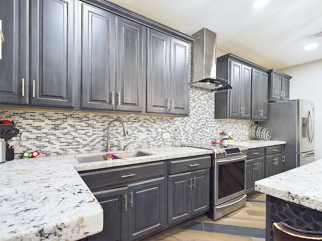 kitchen with light hardwood / wood-style floors, sink, wall chimney exhaust hood, backsplash, and appliances with stainless steel finishes