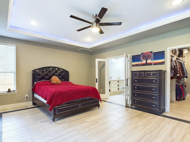 bedroom with a spacious closet, a closet, a tray ceiling, and ceiling fan