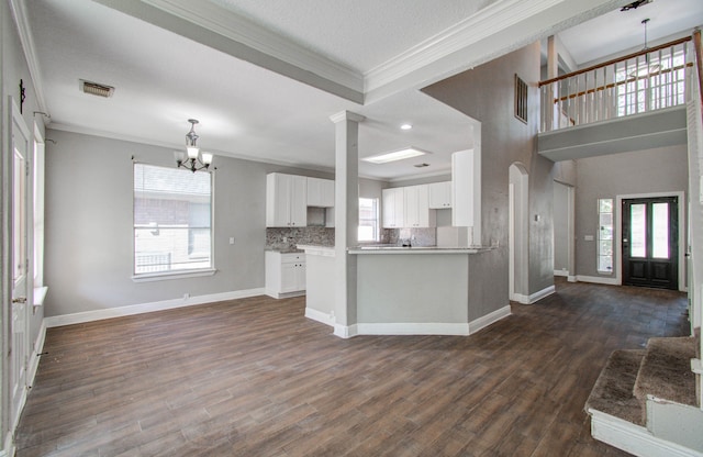 kitchen featuring white cabinets, kitchen peninsula, dark wood-type flooring, and crown molding