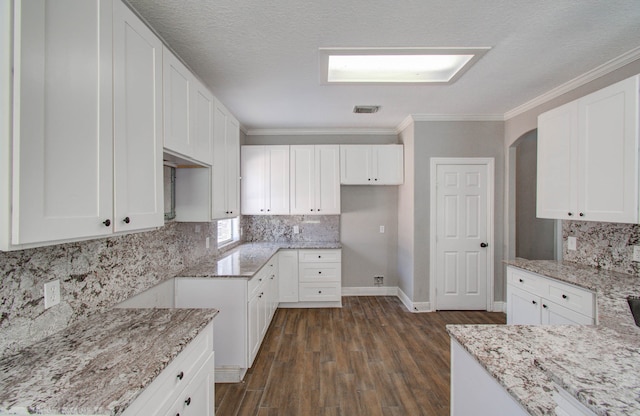 kitchen featuring light stone counters, a textured ceiling, dark hardwood / wood-style floors, white cabinets, and crown molding