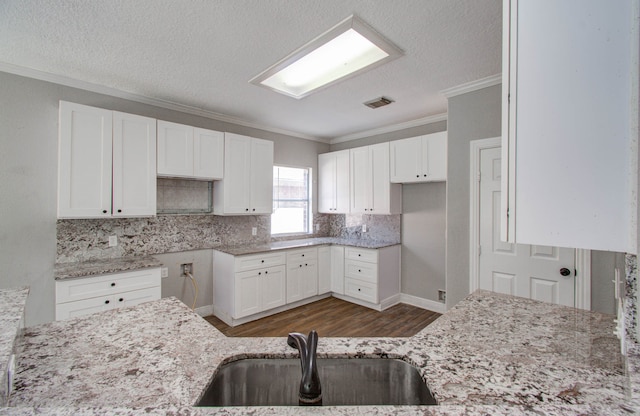 kitchen with crown molding, light stone counters, white cabinetry, and sink