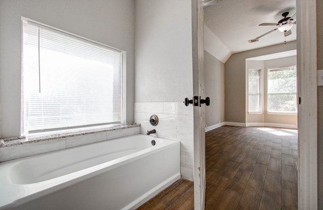 bathroom with wood-type flooring, lofted ceiling, ceiling fan, and a bath