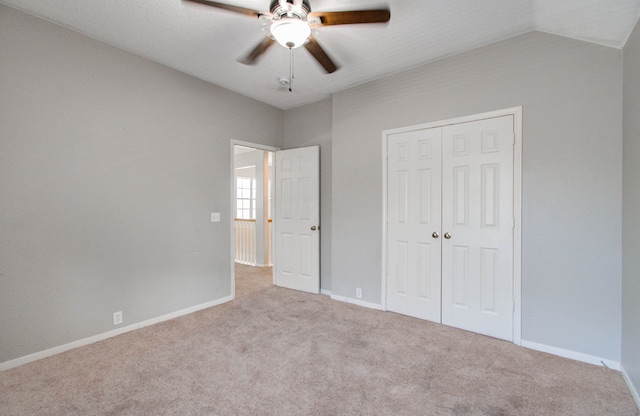 unfurnished bedroom featuring lofted ceiling, light carpet, ceiling fan, and a closet