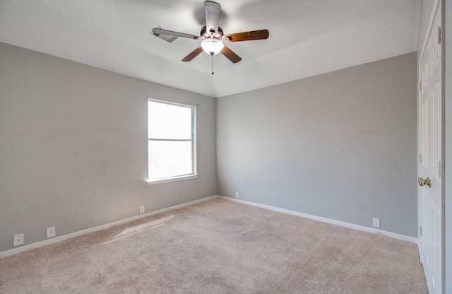 carpeted spare room featuring a textured ceiling, vaulted ceiling, and ceiling fan