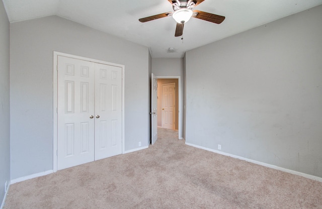 unfurnished bedroom with ceiling fan, a closet, light carpet, and lofted ceiling