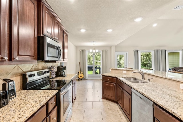 kitchen featuring stainless steel appliances, plenty of natural light, a notable chandelier, and sink