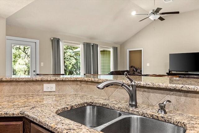 kitchen featuring light stone countertops, sink, ceiling fan, backsplash, and vaulted ceiling