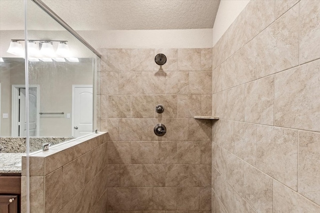 bathroom featuring a tile shower, vanity, and a textured ceiling