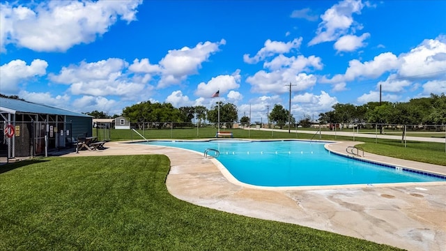 view of pool with a patio and a lawn