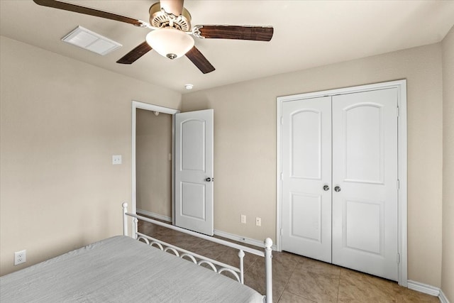 tiled bedroom with ceiling fan and a closet