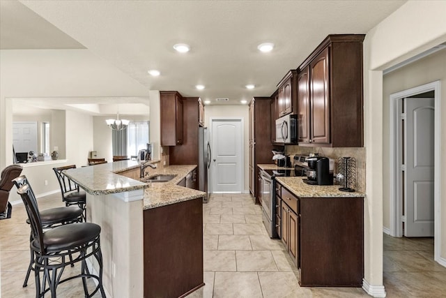 kitchen featuring light stone counters, kitchen peninsula, sink, and appliances with stainless steel finishes