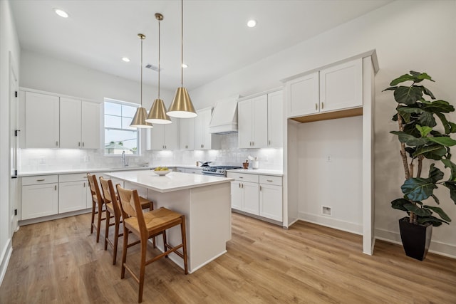 kitchen with white cabinets, a kitchen island, pendant lighting, and custom exhaust hood