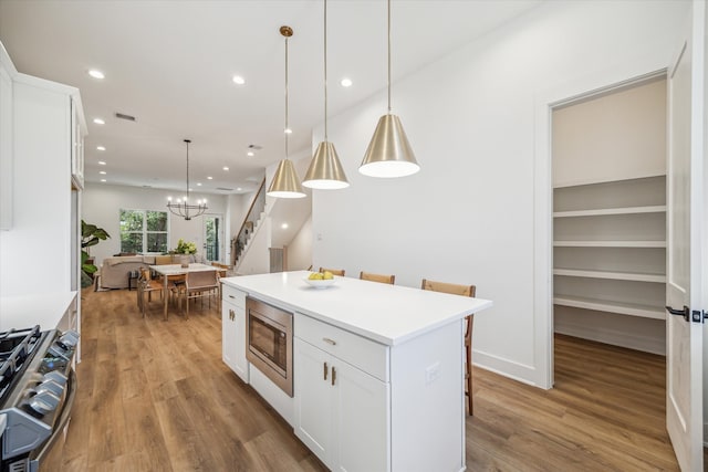 kitchen with white cabinetry, a center island, decorative light fixtures, and appliances with stainless steel finishes