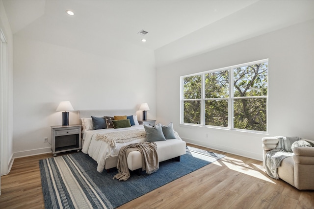 bedroom with multiple windows, hardwood / wood-style floors, and lofted ceiling