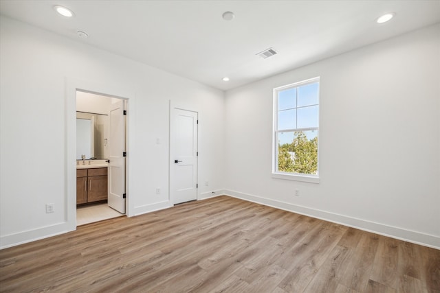 unfurnished bedroom featuring ensuite bath, sink, a closet, and light wood-type flooring