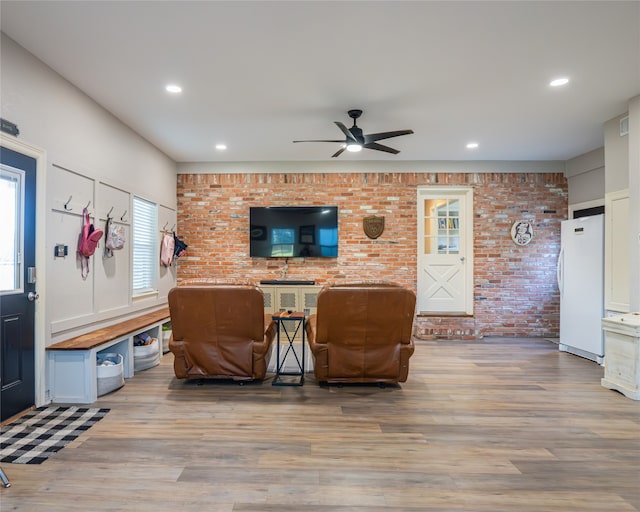 living room featuring ceiling fan, brick wall, and wood-type flooring