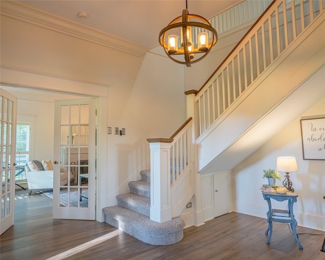 stairs featuring hardwood / wood-style floors, an inviting chandelier, french doors, and ornamental molding