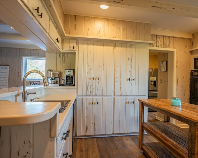 kitchen with dishwasher, wood walls, sink, black oven, and dark hardwood / wood-style flooring