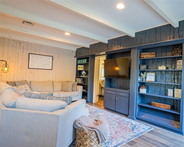 living room featuring beamed ceiling, wood walls, and light hardwood / wood-style flooring