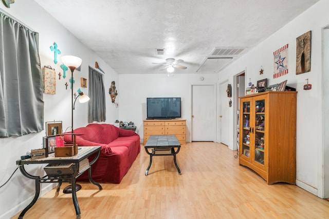 living room featuring ceiling fan, a textured ceiling, and light hardwood / wood-style flooring