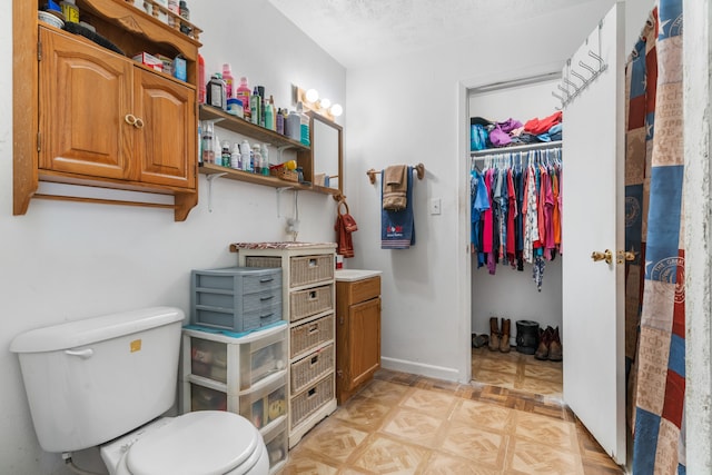 bathroom with a textured ceiling, vanity, and toilet