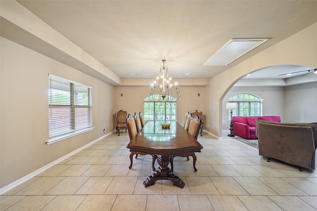 tiled dining area with ceiling fan with notable chandelier