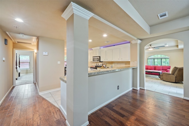 kitchen featuring appliances with stainless steel finishes, white cabinetry, light stone counters, ceiling fan, and light hardwood / wood-style flooring