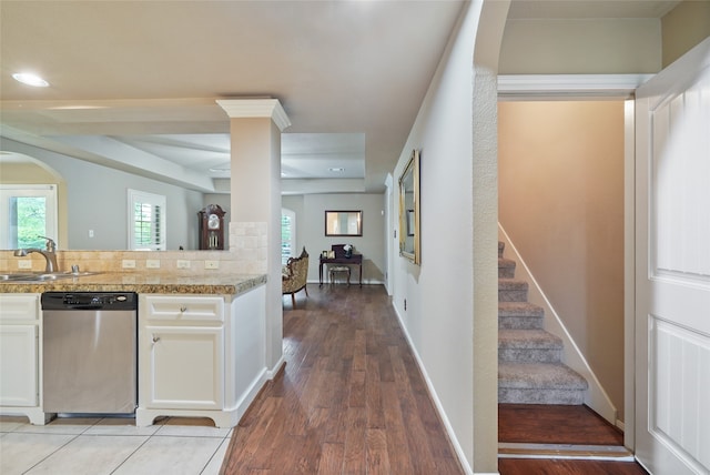 kitchen with decorative backsplash, white cabinetry, dishwasher, light hardwood / wood-style flooring, and sink