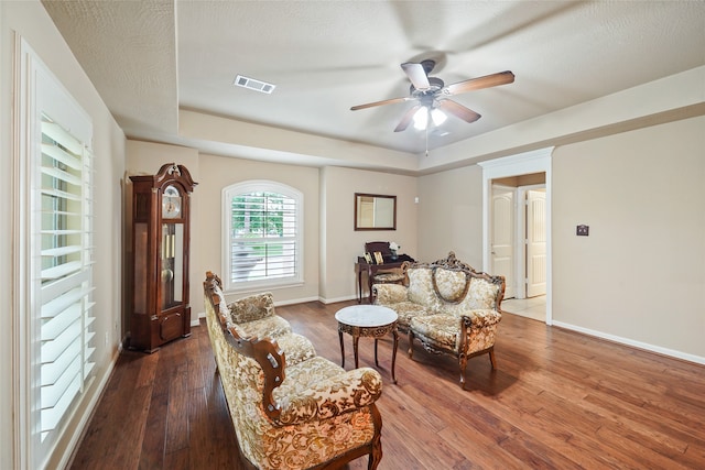 living area with a textured ceiling, dark hardwood / wood-style flooring, and ceiling fan