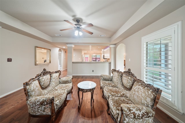 sitting room featuring ceiling fan, decorative columns, and dark wood-type flooring