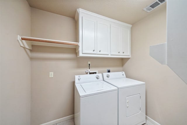 washroom featuring a textured ceiling, washer and dryer, and cabinets