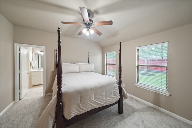 carpeted bedroom with connected bathroom, vaulted ceiling, and ceiling fan