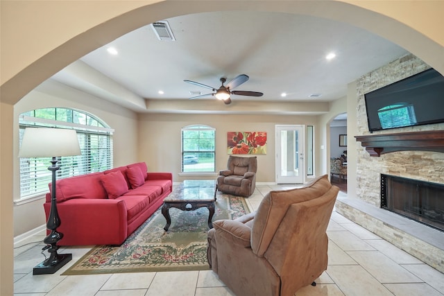 tiled living room featuring a fireplace, ceiling fan, and plenty of natural light