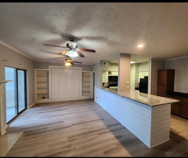 kitchen with ceiling fan, a textured ceiling, light wood-type flooring, and kitchen peninsula