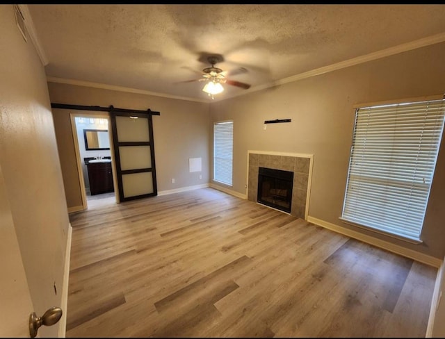 unfurnished living room featuring ceiling fan, light wood-type flooring, a fireplace, and a barn door