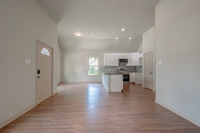 kitchen with light hardwood / wood-style flooring, stainless steel appliances, high vaulted ceiling, and white cabinetry