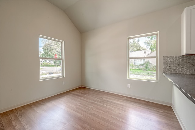 interior space with light hardwood / wood-style floors, lofted ceiling, and a wealth of natural light