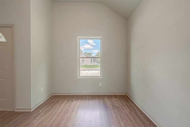 empty room with vaulted ceiling and light hardwood / wood-style floors