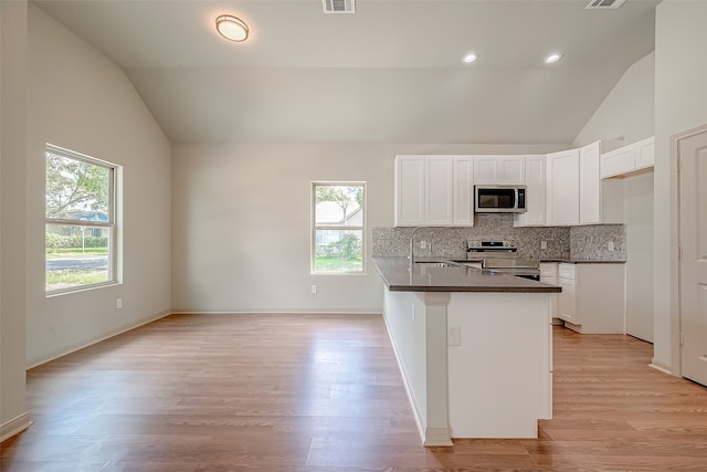 kitchen with light wood-type flooring, decorative backsplash, stainless steel appliances, and white cabinets