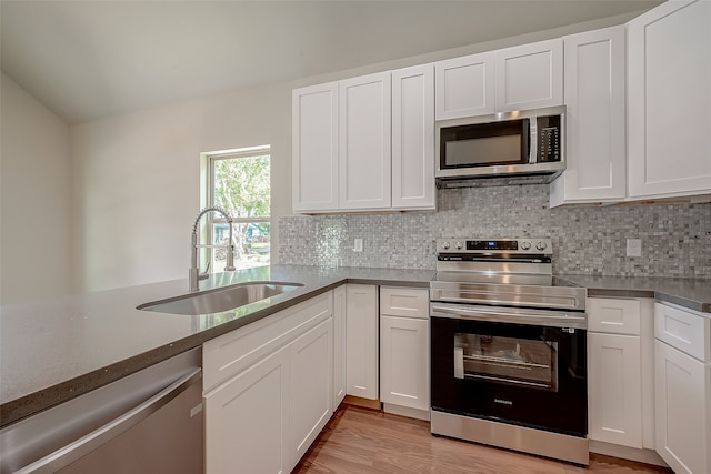 kitchen with appliances with stainless steel finishes, light hardwood / wood-style floors, white cabinetry, and sink