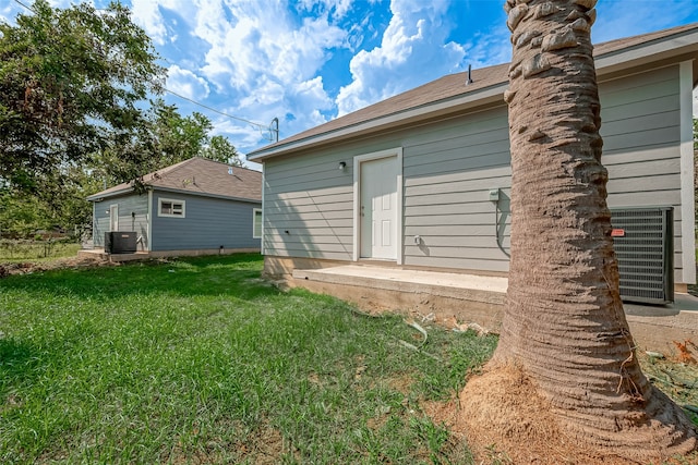 rear view of property featuring a lawn and cooling unit