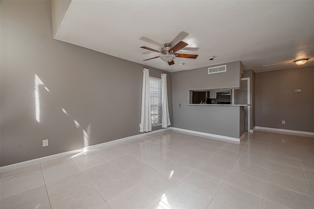 empty room with ceiling fan, light tile patterned floors, and a textured ceiling