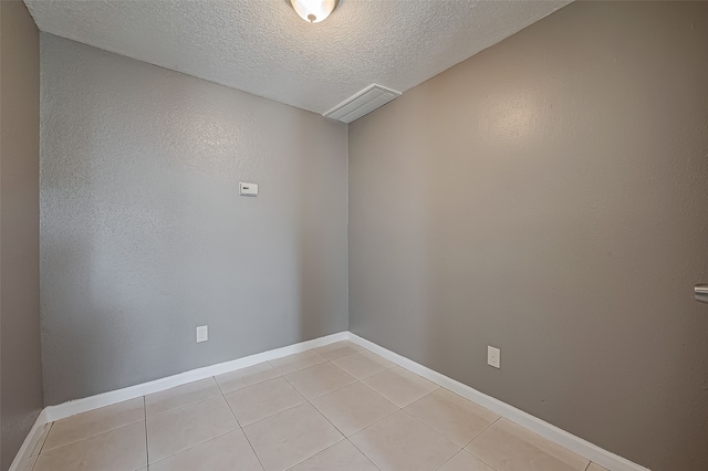 unfurnished room featuring a textured ceiling and light tile patterned floors